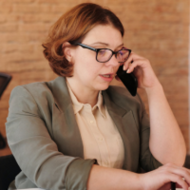 Woman with glasses and grey jacket on the phone