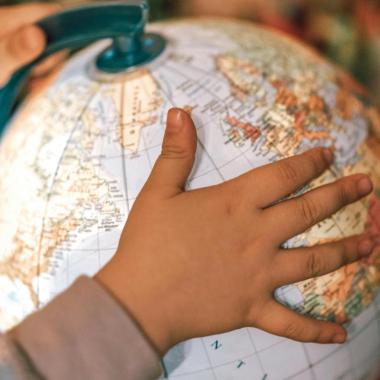 child's hand on globe