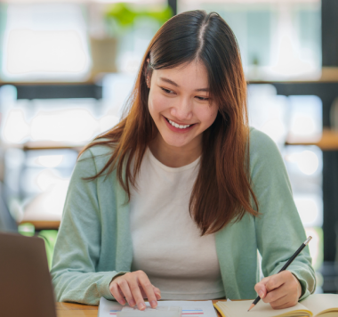 Woman sat at laptop following training manual