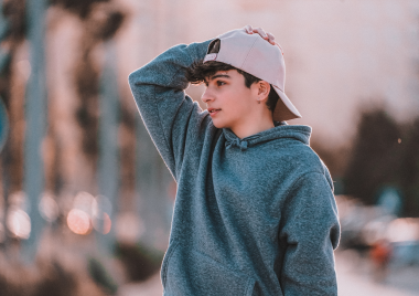 Boy wearing baseball cap with hand on his head
