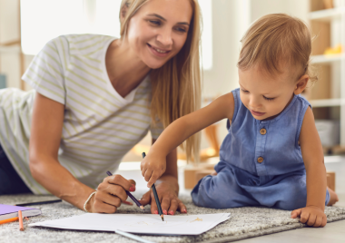 woman smiling at a child whilst drawing
