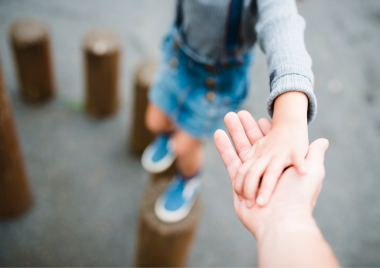 Child reaching out and holding adults hand