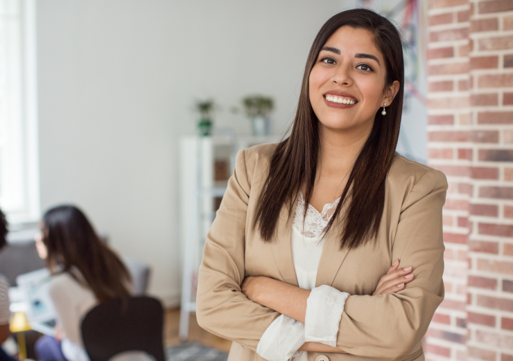 woman with long hair wearing a beige blazer looking at the camera
