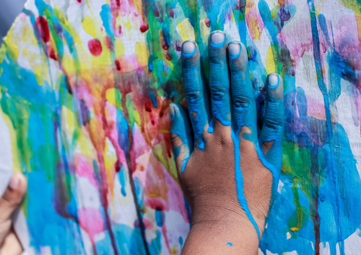 Child's painted hand on paint splattered wall